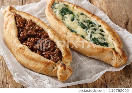 Traditional turkish baked dish pide with ground meat, cheese, spinach and spicy close-up on wooden board. Horizontal 119762003