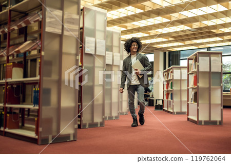 Curly-haired young man in eyeglasses in the library Curly-haired young man in eyeglasses in the library 119762064
