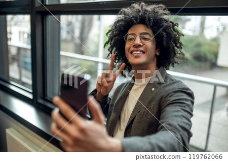 Smiling young man near the window with a phone in hands 119762066