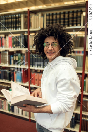 Curly-haired young man in eyeglasses in the library 119762146