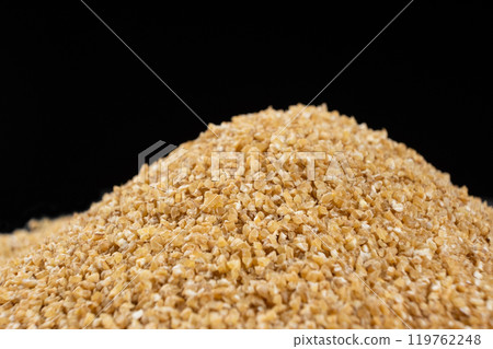 Pile of raw uncooked wheat groats on a black background Pile of raw uncooked wheat groats on a black background 119762248