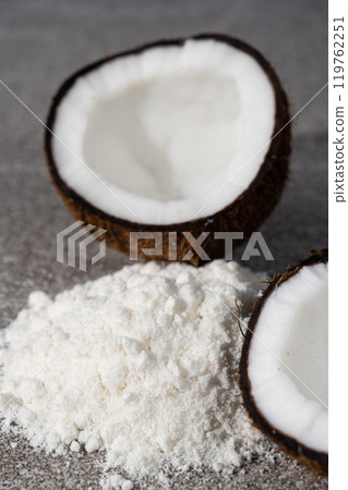 Coconut flour among coconut halves on gray stone background. Coconut flour among coconut halves on gray stone background. 119762251