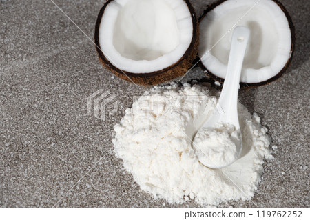 Coconut flour among coconut halves on gray stone background, place for text Coconut flour among coconut halves on gray stone background, place for text 119762252