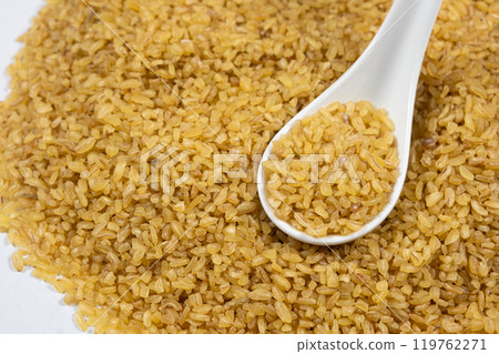 Uncooked bulgur cracked wheat in a spoon close-up Uncooked bulgur cracked wheat in a spoon close-up 119762271