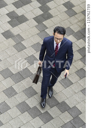 Aerial view of a middle-aged businessman walking in the city Aerial view of a middle-aged businessman walking in the city 119762789