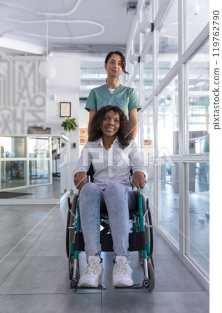 Female nurse carrying a wheelchair with an african american woman 119762790