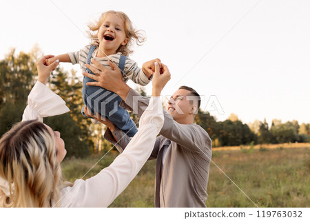 Happy parents cheerfully holding baby in the park 119763032
