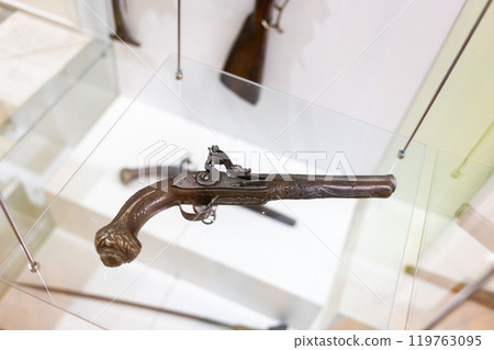 Top view of decorated antique weapon with intricate wood pattern. A vintage 19th century pistol on display at the museum Top view of decorated antique weapon with intricate wood pattern. A vintage 19th century pistol on display at the museum 119763095