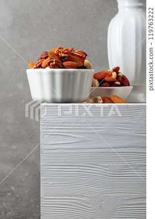 Dried fruits and nuts on a white wooden table. 119763222
