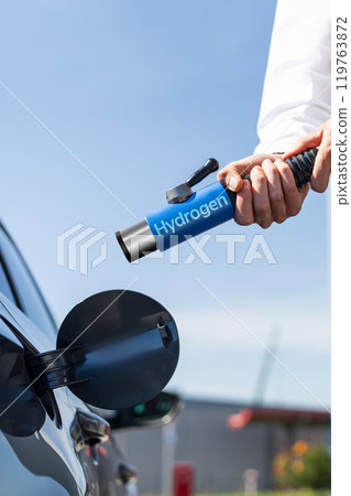 Man holds a hydrogen fueling nozzle on a hydrogen filling station. Refueling car with hydrogen fuel. Man holds a hydrogen fueling nozzle on a hydrogen filling station. Refueling car with hydrogen fuel. 119763872