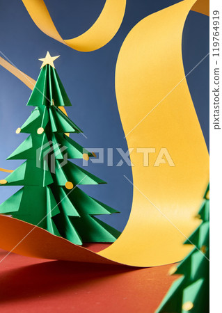 Abstract style photography of Christmas conceptual, decorated with yellow ribbons and green christmas trees, over blue background. Front close up view, space for presentation 119764919