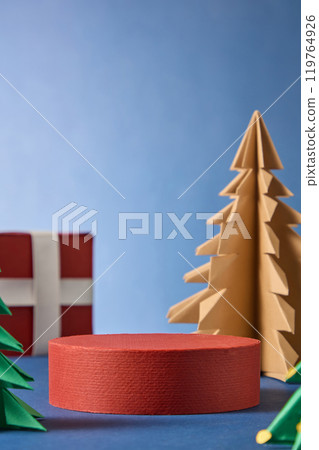 The product promotional image on a round red platform placed in the center, next to a red gift box, and a brown and green paper pine tree in a blue space, creates a Christmas atmosphere. 119764926