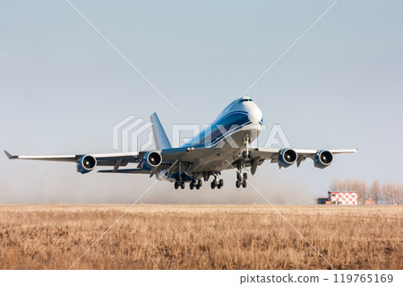 Wide body cargo transport airplane takes off leaving behind a cloud of dust Wide body cargo transport airplane takes off leaving behind a cloud of dust 119765169