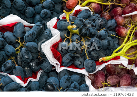 Blue and red sweet grapes on boxes in supermarket, top view. Blue and red sweet grapes on boxes in supermarket, top view. 119765428