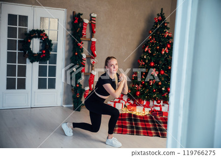 blonde woman doing fitness sport gymnastics at christmas tree for new year 119766275