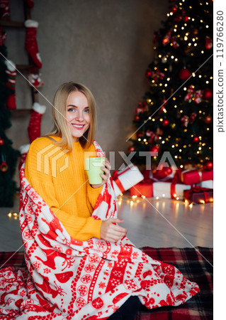 Beautiful woman with gifts and mug of coffee at christmas tree for new year 119766280