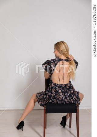 Beautiful blonde woman in dress shows her back 119766288