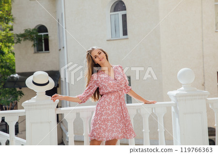 Beautiful woman in summer pink dress walking the streets 119766363