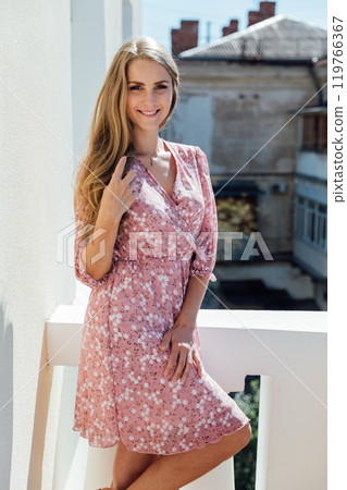 fashion blonde woman in summer light pink dress smiling 119766367