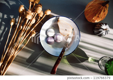 Still life with fruits in cozy interior. Plate with pear, macaroons, pumpkins on a table. Rustic lifestyle at home concept. Confectionery, meringue, sweets on a kitchen. Autumnal fruits, vegetables. Still life with fruits in cozy interior. Plate with pear, macaroons, pumpkins on a table. Rustic lifestyle at home concept. Confectionery, meringue, sweets on a kitchen. Autumnal fruits, vegetables. 119766379