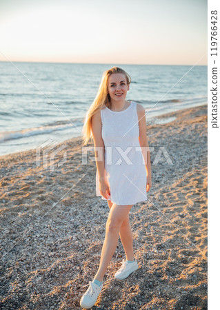 Beautiful blonde woman walking on the beach of the sea Beautiful blonde woman walking on the beach of the sea 119766428