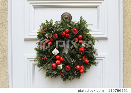 Christmas wreath with branches and red apples on a white door Christmas wreath with branches and red apples on a white door 119766561