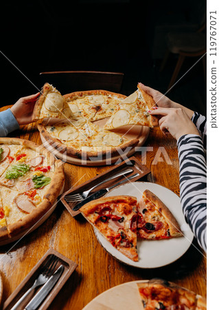 Assorted pizzas with fresh toppings shared among friends for a cozy meal experience Assorted pizzas with fresh toppings shared among friends for a cozy meal experience 119767071