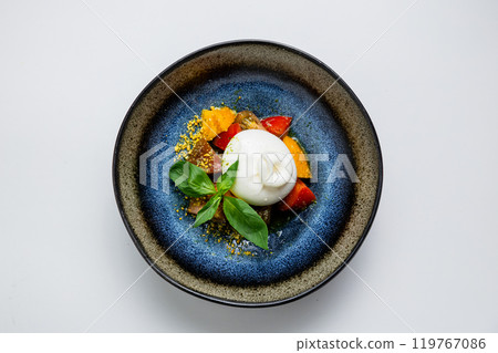Fresh burrata with colorful tomatoes, basil, and pistachio crumbs. Gourmet appetizer perfection 119767086