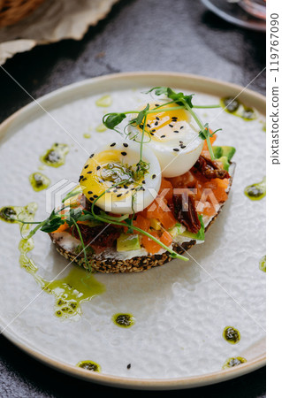 Gourmet toast with smoked salmon, boiled eggs, sun-dried tomatoes, and herbs served with black tea 119767090