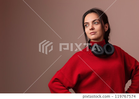 beautiful woman in red sweater and headphones on dark background. copy space 119767574
