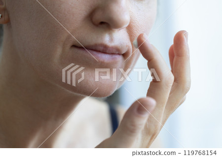 Woman applying cream on nasolabial wrinkles. 119768154