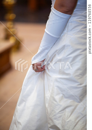 An Elegant Bride Beautifully Holding Her Wedding Dress with Grace and Poise in Her Hands An Elegant Bride Beautifully Holding Her Wedding Dress with Grace and Poise in Her Hands 119768556