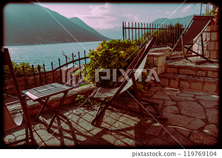 Pair of sun loungers with coffee table on terrace. Retro style photo Pair of sun loungers with coffee table on terrace. Retro style photo 119769104