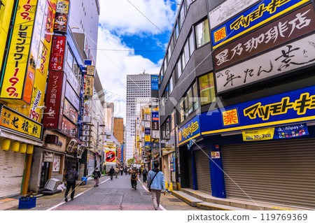 Tokyo cityscape in Japan: Shinjuku West Exit drinking district. People commuting to work in the office district in the back... = 21st 119769369