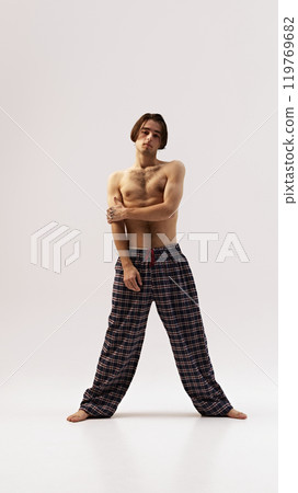 Bare-chested man in casual checkered pants with arms crossed, capturing relaxed and natural look against white studio background. Bare-chested man in casual checkered pants with arms crossed, capturing relaxed and natural look against white studio background. 119769682