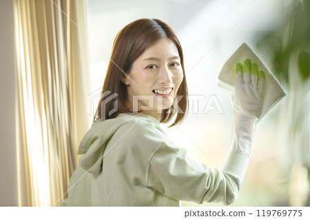 A middle-aged woman wiping windows in the living room A middle-aged woman wiping windows in the living room 119769775