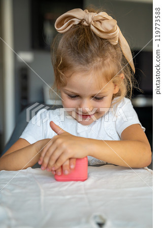 Little girl with a stamp with a name for signing children's things. Identification of personal clothing. Little girl with a stamp with a name for signing children's things. Identification of personal clothing. 119773588