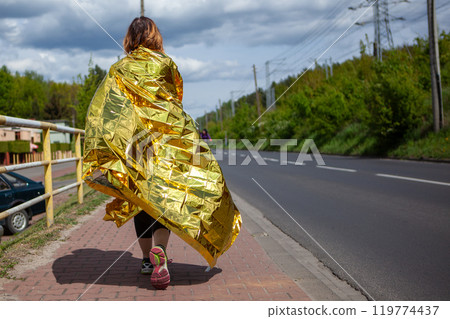 Woman Walking with Thermal Blanket After Sports Race 119774437
