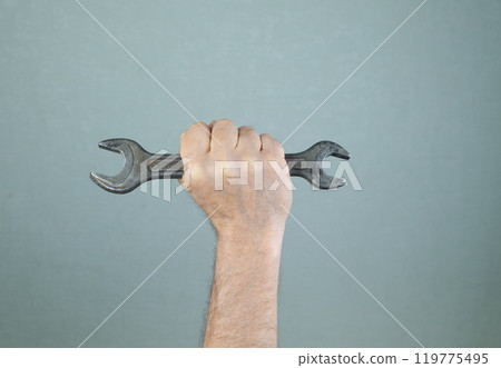 Male hand holding metal wrench. Working tool 119775495