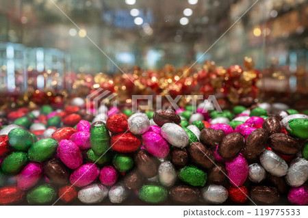 Lots of candies in colorful packages on the shop window. Colored candy in the form of eggs. 119775533