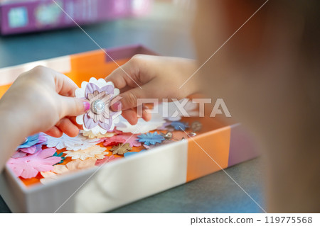 Small, colorful paper flowers in child hands, little girl creativing of 3D flowers. Child development toy Small, colorful paper flowers in child hands, little girl creativing of 3D flowers. Child development toy 119775568