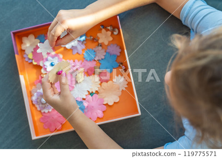 Small, colorful paper flowers in child hands, little girl creativing of 3D flowers. Child development toy Small, colorful paper flowers in child hands, little girl creativing of 3D flowers. Child development toy 119775571