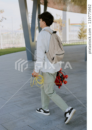 Unrecognizable teen boy with beige backpack and red robot with yellow wires in hands walking Unrecognizable teen boy with beige backpack and red robot with yellow wires in hands walking 119775662