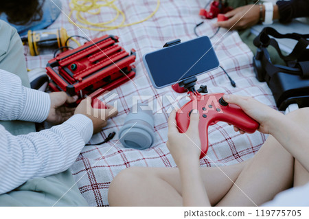High angle shot of unrecognizable kid holding red joystick with set smartphone while his friends playing with robot in background 119775705