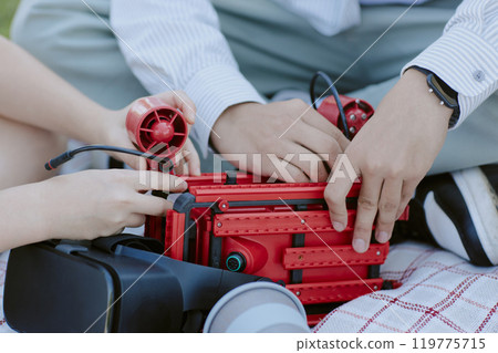 Medium closeup of unrecognizable kids making robot on blanket together 119775715