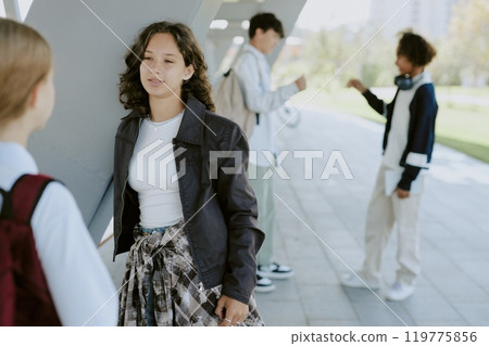 Teen besties standing outside and chatting while waiting school lessons 119775856