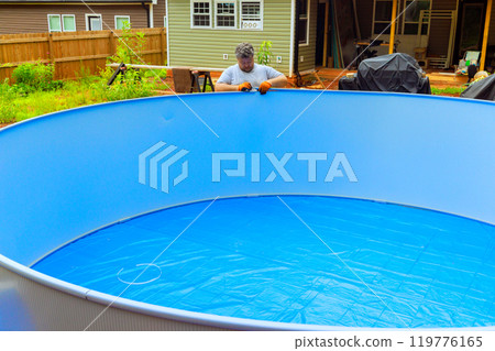 An above ground pool metal frame is being installed by worker 119776165