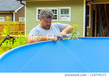 Worker is engaged in installation of metal frame of aboveground pool 119776171