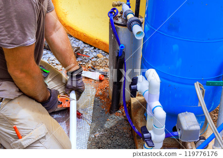 Water supply pipe made of PVC is being connected to pump house of an artesian well system Water supply pipe made of PVC is being connected to pump house of an artesian well system 119776176