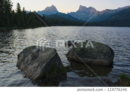 Big stones on Shore of large mountain lake Svetloye, surrounded by coniferous forest in Ergaki. Twilight landscape 119776240